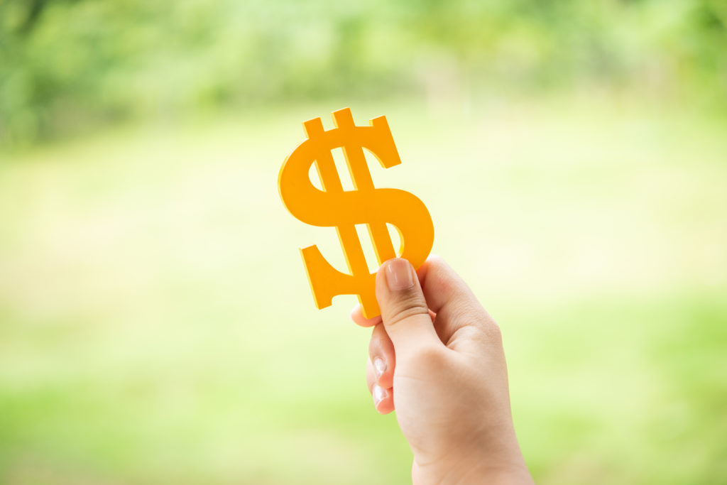 The hand of children to hold a golden symbol dollar with blurred green background. Showed saving, financial investment for make future dream come true or education plan, sustained with finance concept